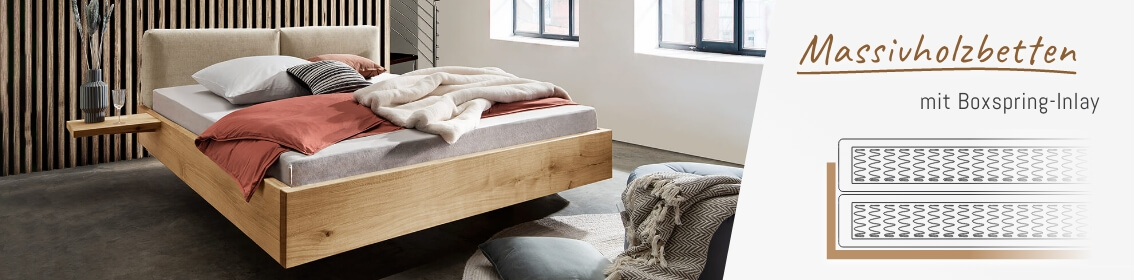 Massivholzbett Schwebendes Massivholzbett mit Boxspring-Inlay, beiges Kopfteil, rotbraune Bettdecke und Kissen